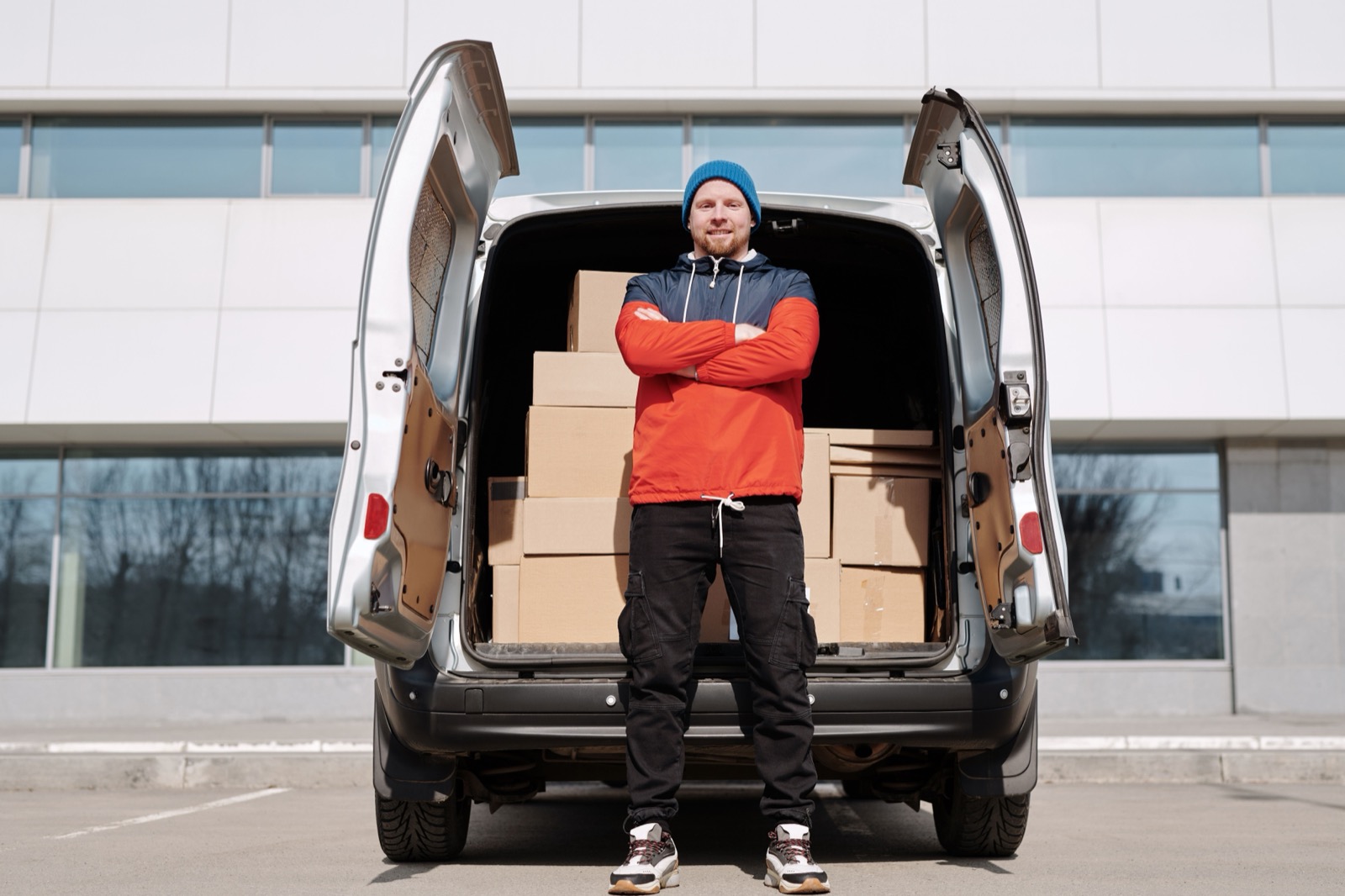 Owner of a small delivery business beside a van loaded with boxes